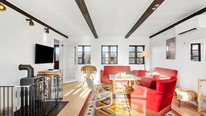 Una sala de estar moderna con chimenea, sofás rojos, televisor y ventanas amplias.