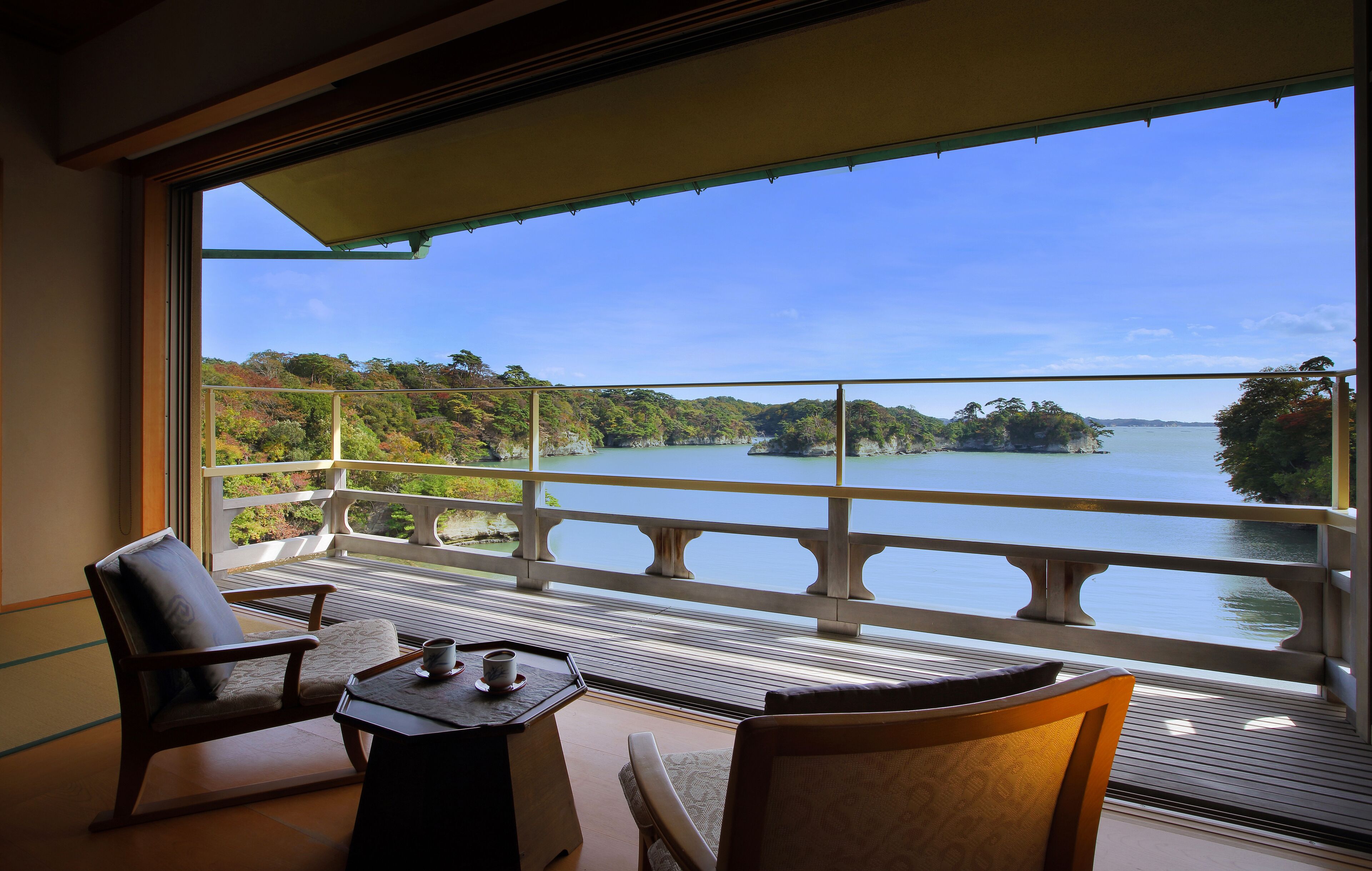 A balcony with a view of a lake and forested hills.