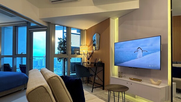 Una sala de estar moderna con un sofá, una mesa de centro, un televisor y vistas de la ciudad.