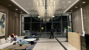 Un vestíbulo moderno con una escalera central, zonas de estar y un mostrador de recepción.