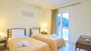 A hotel room with two beds, a desk, and a window with curtains. - 3 Bedroom Villa, Private Pool, Agios Stefanos (Agios Stefanos)