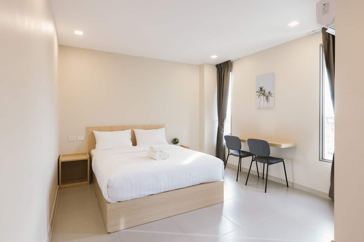 A modern hotel room with a large bed, a desk, and a chair.