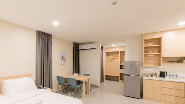 A hotel room with a bed, a desk, chairs, a kitchenette, and a bathroom. - Good Nine Hotel (Bang Bo)