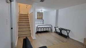 Een ruime woonruimte met een bank, een bed, een trap en een kleine tafel.