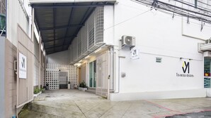 A hotel entrance with a covered walkway, a gated entrance, and a sign indicating the hotel name. - TAKKA Hotel (Bangkok)