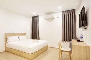 Habitació d'hotel amb un llit, escriptori, cadira, aire condicionat i televisió.