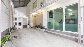 A clean, modern office space with a check-in area, potted plants, and a glass door entrance. - TAKKA Hotel (Bangkok)