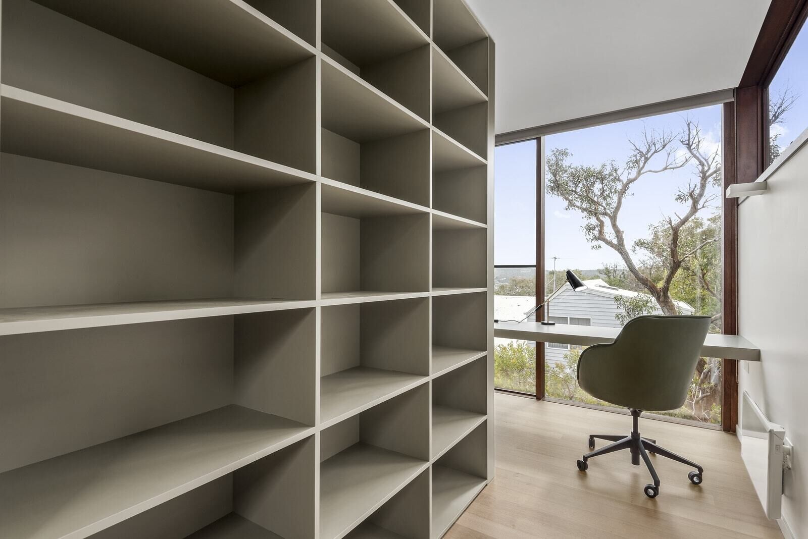 Een moderne kantoorruimte met een groot raam, een bureau en een stoel.