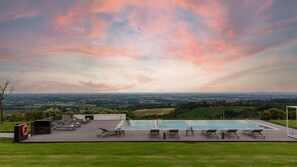 A pool area with lounge chairs and a lifebuoy, surrounded by a grassy lawn and a scenic view of the countryside. - Santa Maria Maddalena 10 Emma Villas (Castel San Pietro Terme)