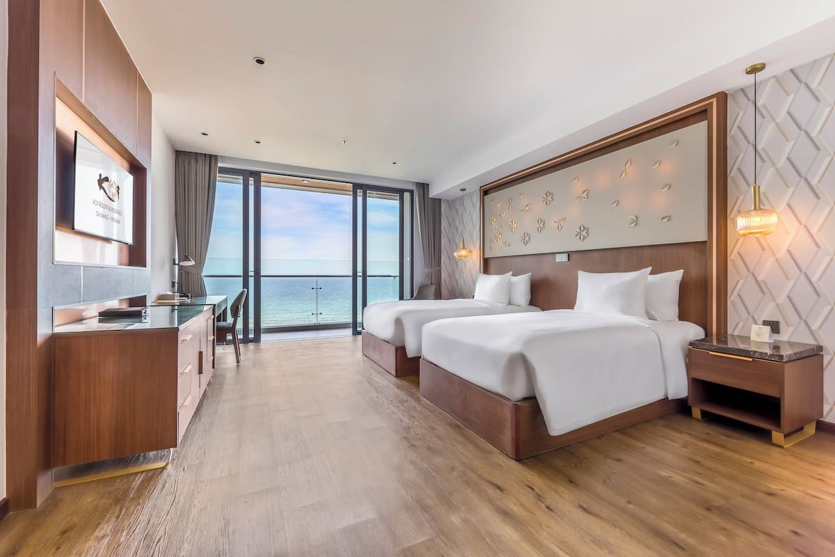Une chambre d’hôtel moderne avec un grand lit, un bureau et une vue sur l’océan.