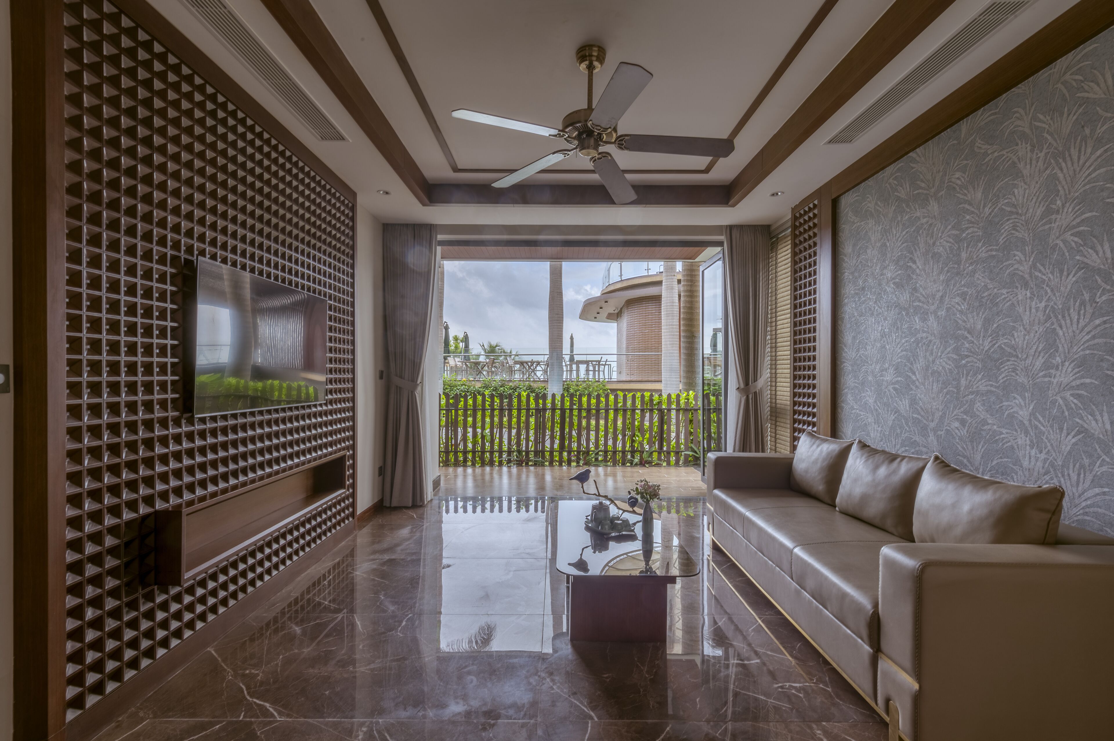 A modern living room with a flat-screen TV, a ceiling fan, a sofa, and a coffee table.