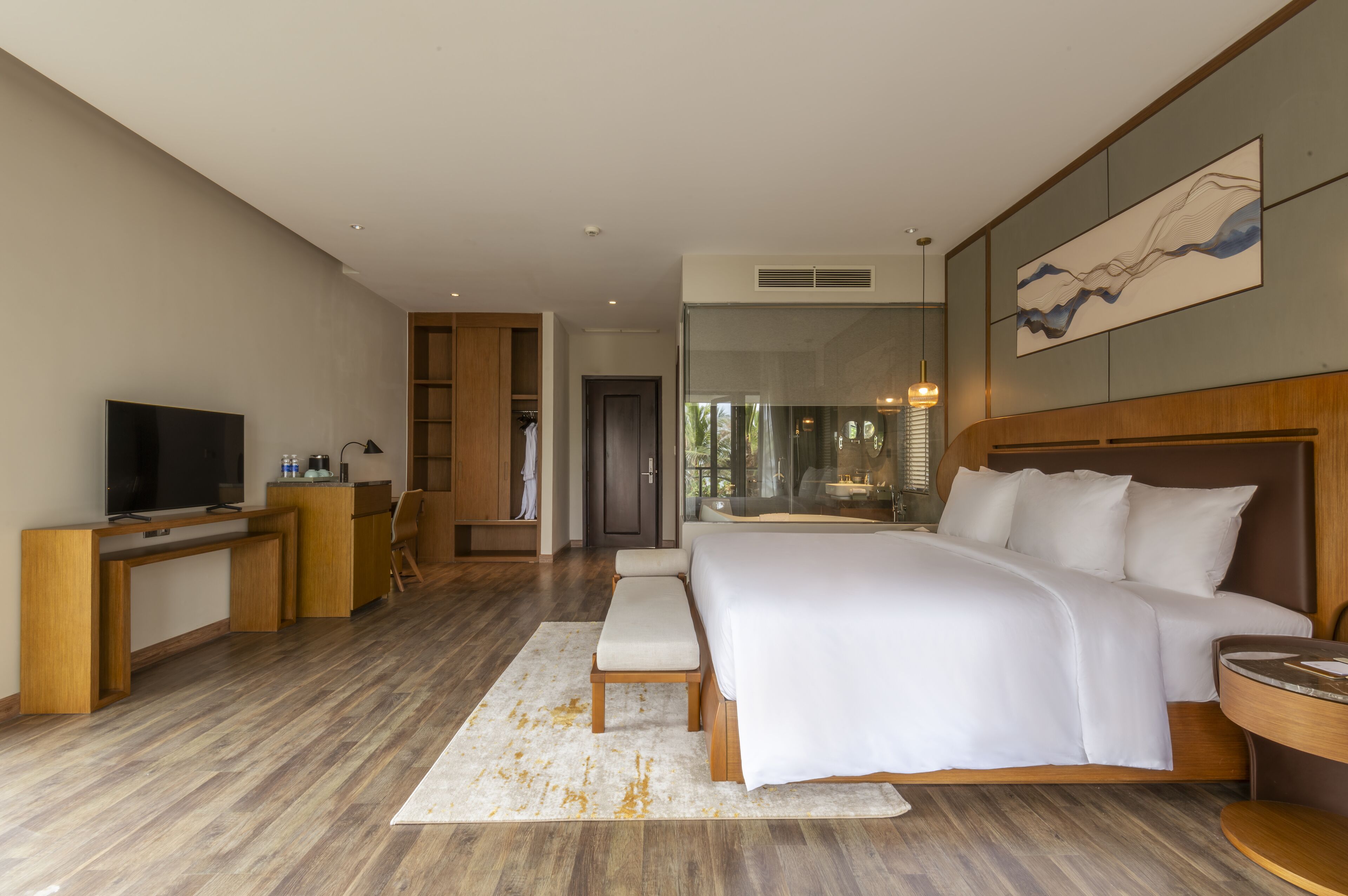 A modern hotel room with a large bed, a desk, a television, and a view of the outdoors.