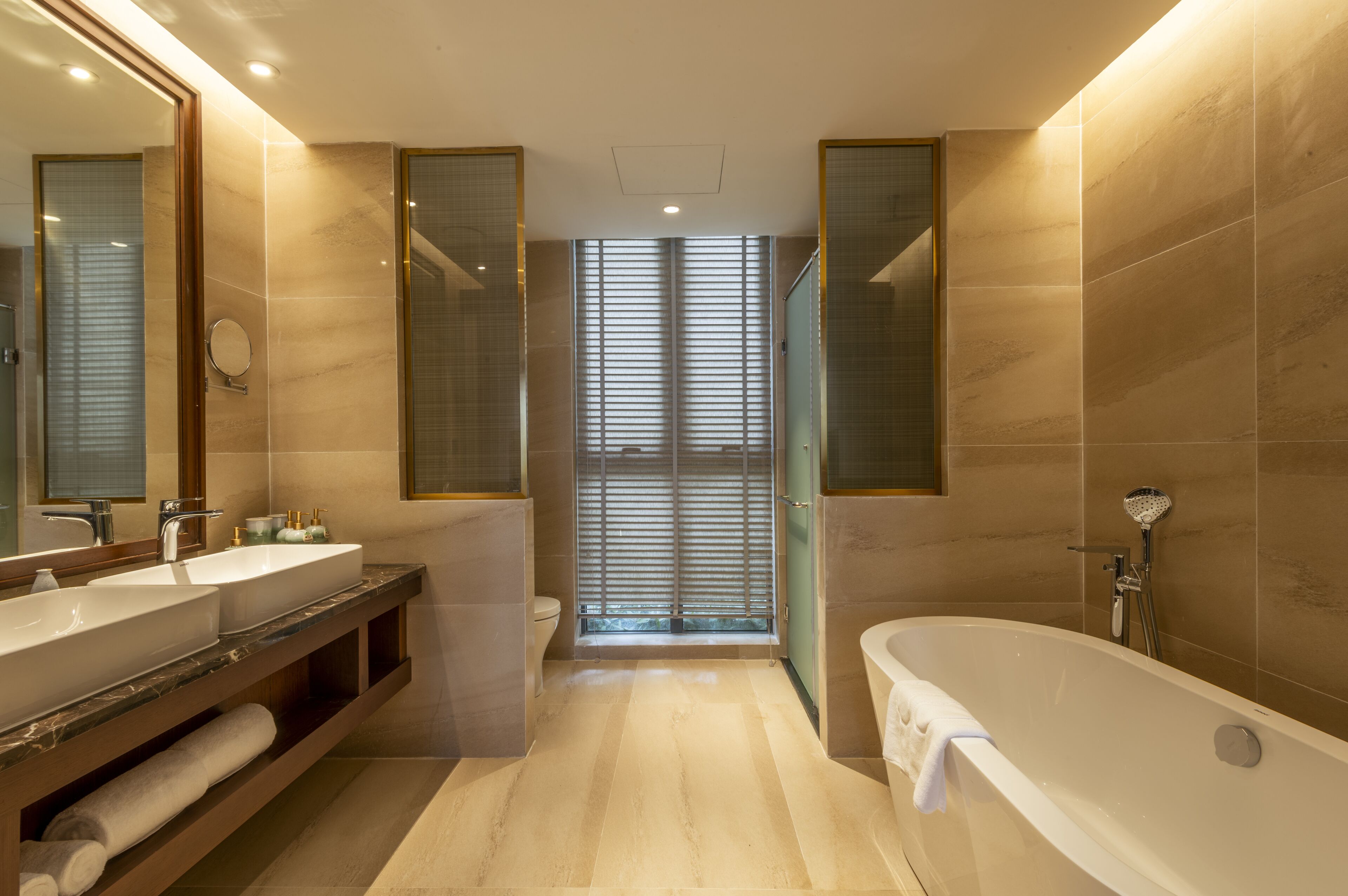 Un baño moderno con una bañera grande, dos lavamanos y un mueble tocador con espejo.