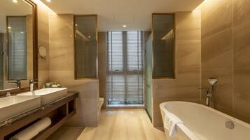 Un baño moderno con una bañera grande, dos lavamanos y un mueble tocador con espejo.