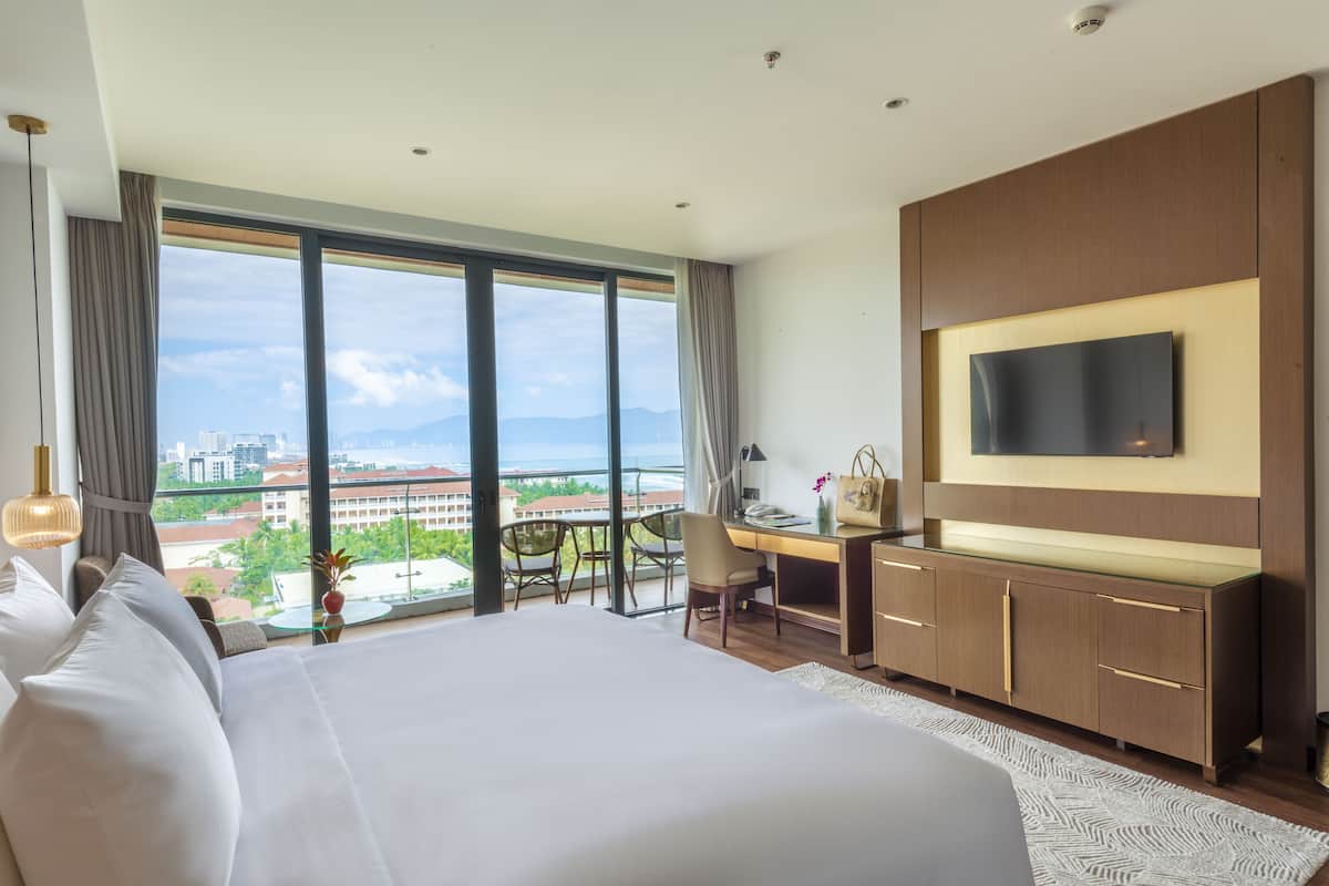 Une chambre d’hôtel avec un grand lit, un bureau, une télévision et une vue sur la ville.