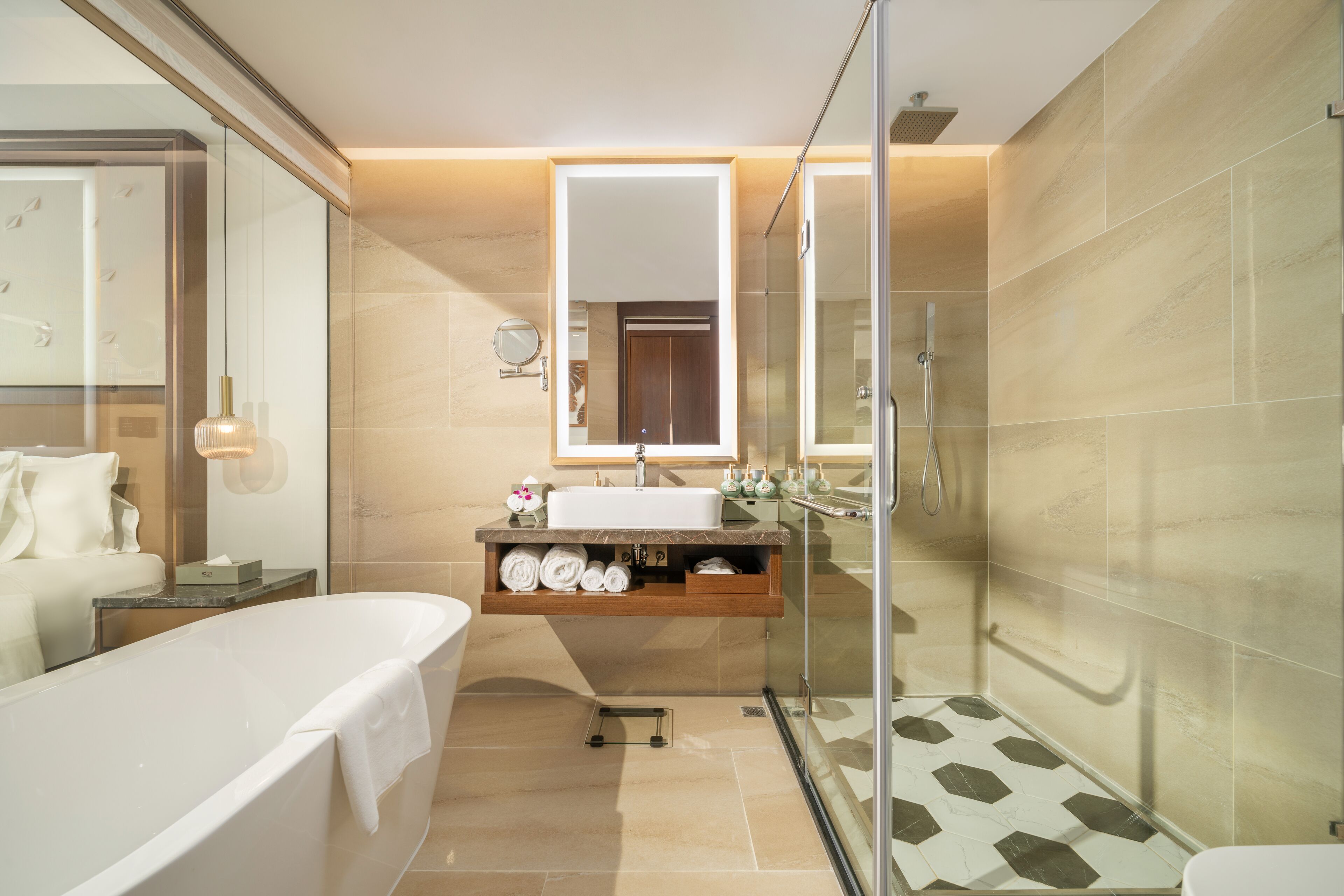 Un baño moderno con ducha de vidrio, una bañera independiente y un lavabo con espejo y toallero.