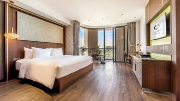 Habitación de hotel con una cama grande, un escritorio, un televisor y un balcón con vistas.