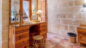 A wooden vanity with a mirror, a stool, and a lamp. - Ta'leli Pool Farmhouse in Gozo (Gharb)