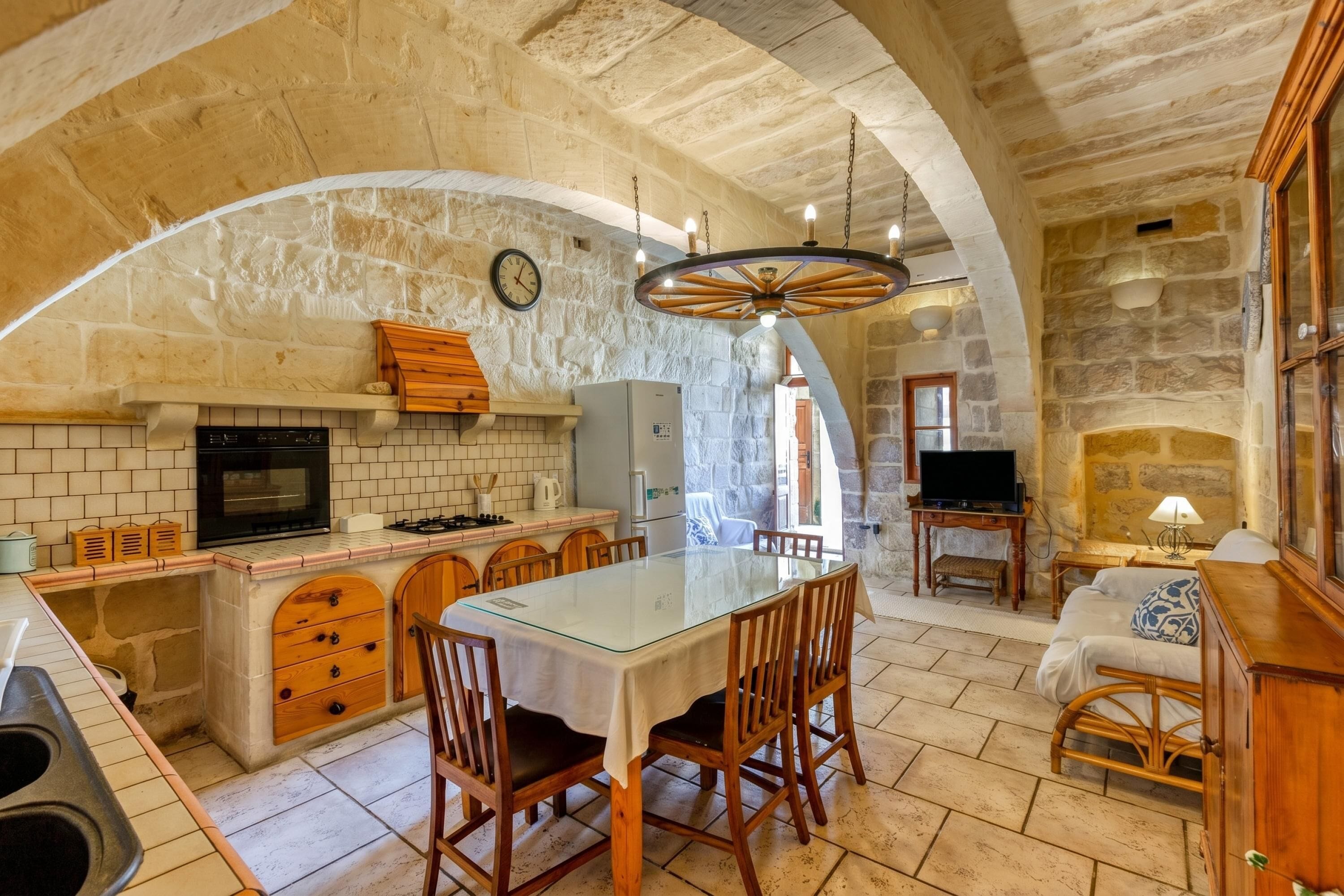 A spacious kitchen with a large island, stone walls, and a rustic chandelier.