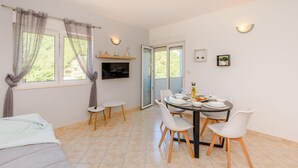 A dining area with a round table, white chairs, and a TV mounted on the wall. - Lovely apartment in Klek with swimming pool (Klek)