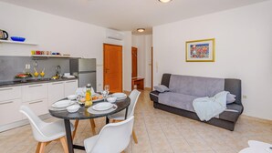 A modern kitchen with a dining area, a grey sofa, and a tiled floor. - Lovely apartment in Klek with swimming pool (Klek)