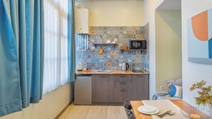 Una cucina compatta con piastrelle a mosaico, un forno a microonde e un lavello.