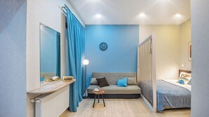 Una camera da letto moderna con un divano letto, un comodino con una lampada, uno specchio e un orologio appeso al muro.