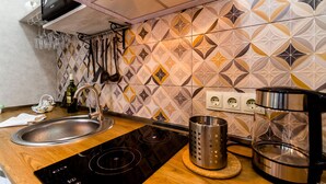 Una cucina moderna con piano cottura a induzione nero, lavello in acciaio inossidabile e schienale decorato.