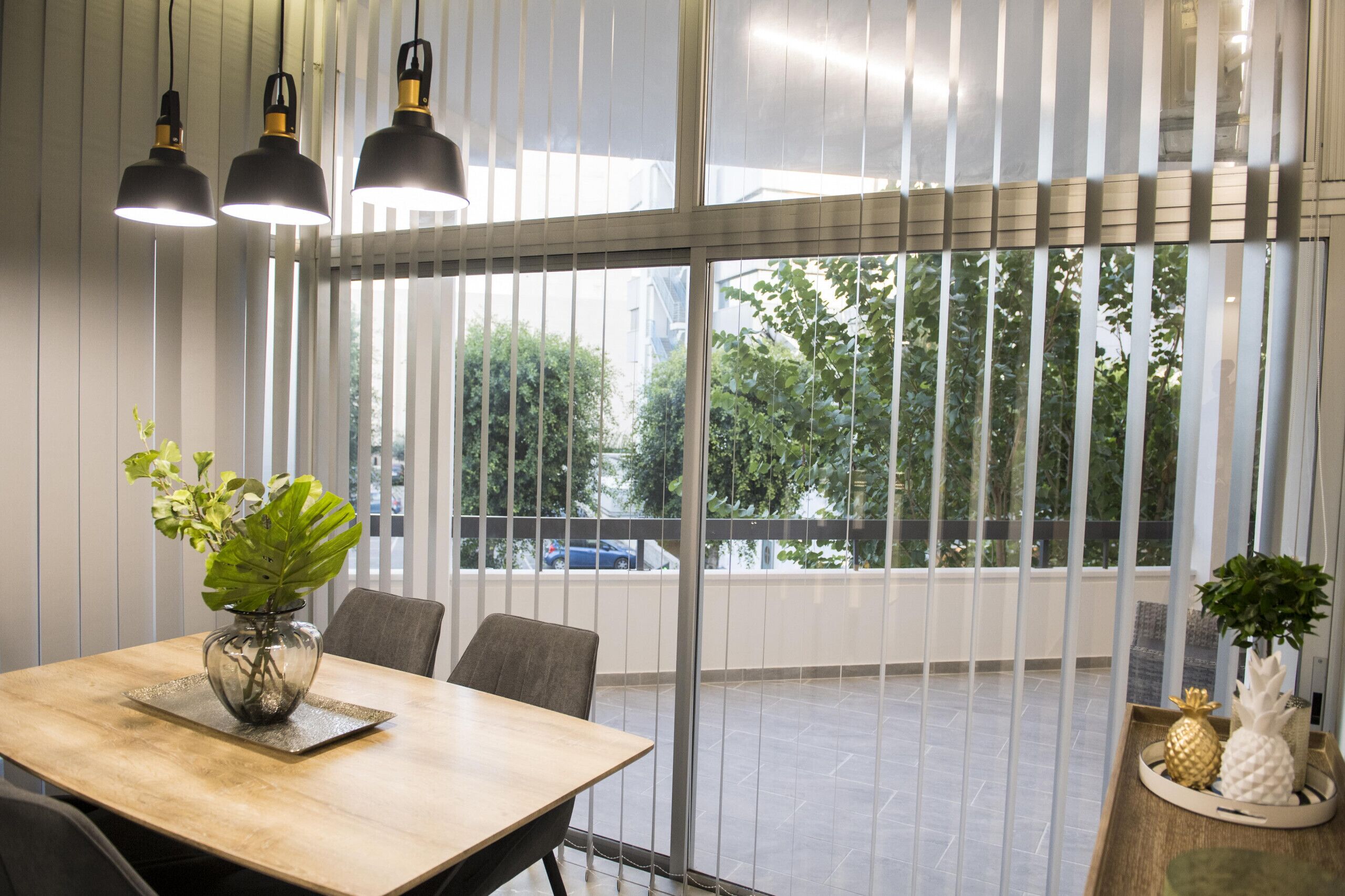 A modern dining area with a wooden table, chairs, and pendant lights.