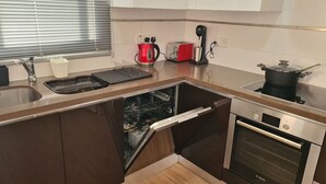 A compact kitchen with a dishwasher, oven, and a kettle. - STAY Mystique City Penthouse (Limassol)