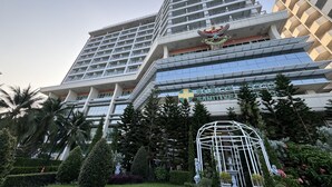 A modern hotel with a prominent wing extending from the main building, featuring a large emblem at the top. - Sriracha Avenue (Si Racha)