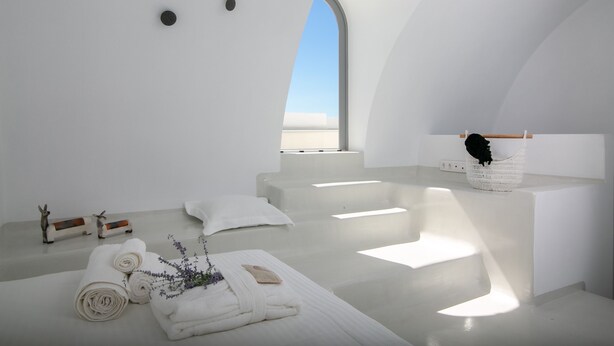 Une chambre moderne et minimaliste, dotée d’une grande verrière, d’une baignoire blanche, ainsi que de serviettes et d’articles de toilette soigneusement disposés.