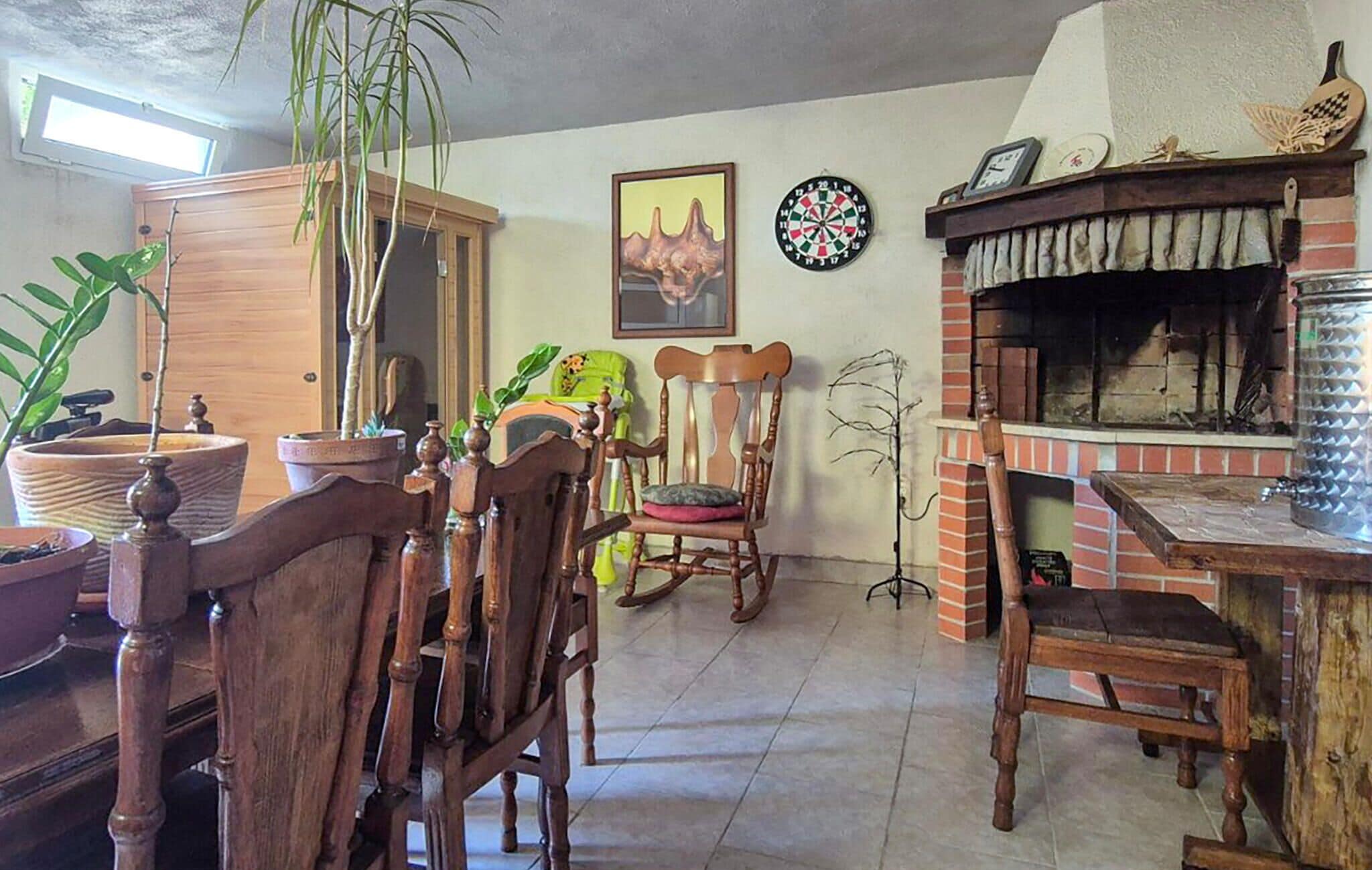 Una sala de estar acogedora con una mesa de comedor de madera, sillas, una planta en maceta, un dardo y una chimenea de ladrillo.