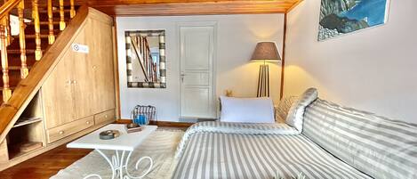 A cozy bedroom with a bed, a nightstand, a lamp, and a painting on the wall.