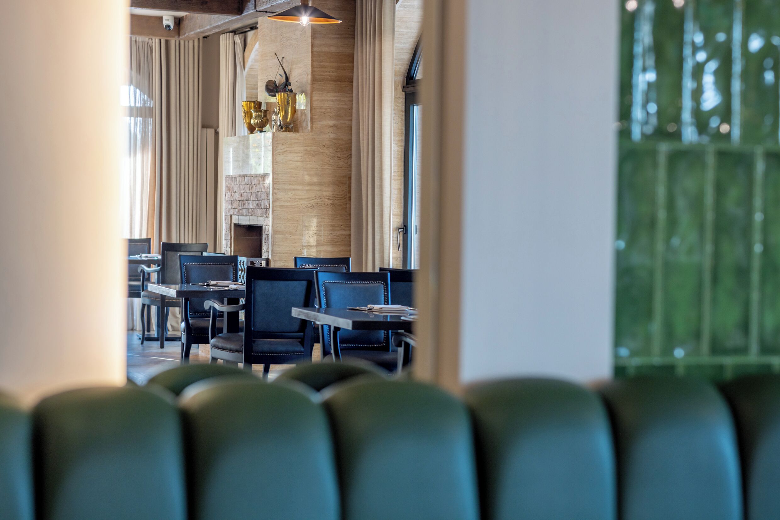 L’intérieur d’un restaurant au design moderne, avec des sièges en cuir, une cheminée et une vue sur l’extérieur par une porte.