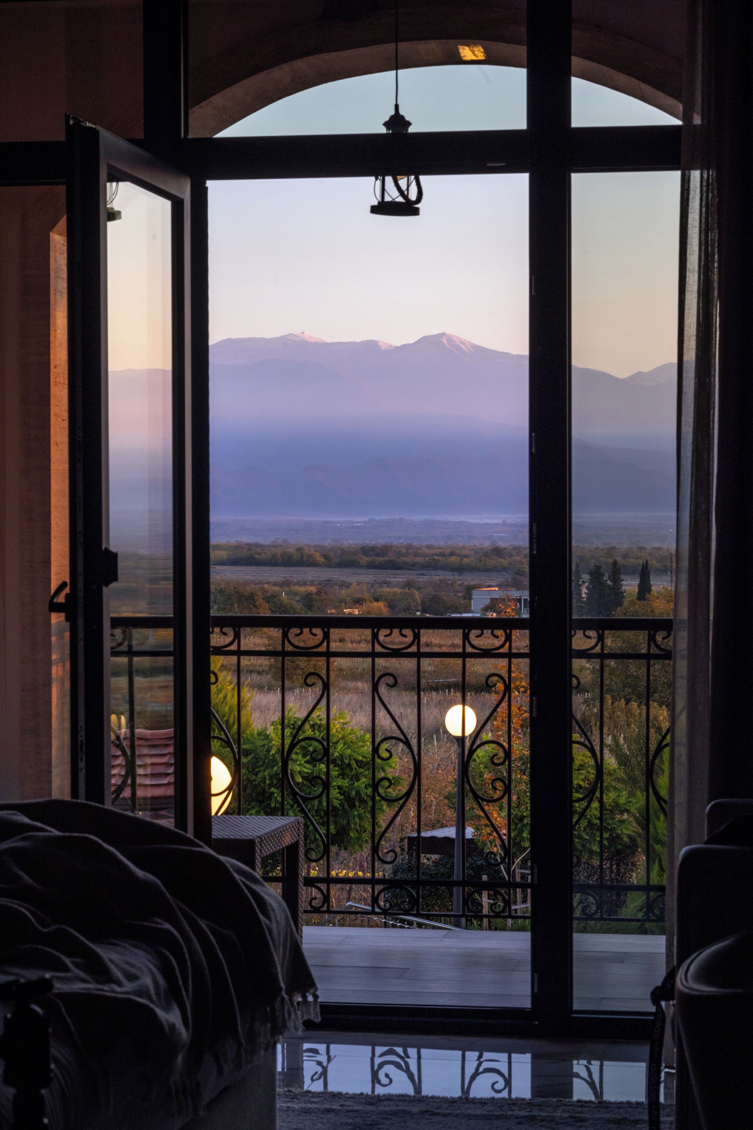 Un balcón con vistas a montañas y un atardecer.