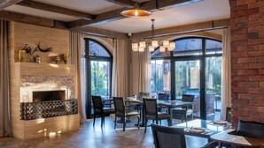 A spacious dining area with a brick fireplace, large windows, and modern lighting fixtures. - Panorama Kakheti Resort (Gurjaani)