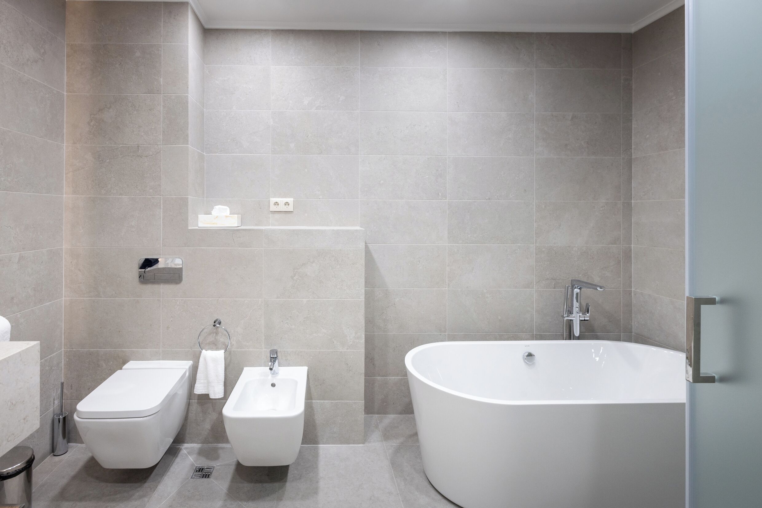 Une salle de bain moderne avec une baignoire sur pieds, un bidet et un lavabo.