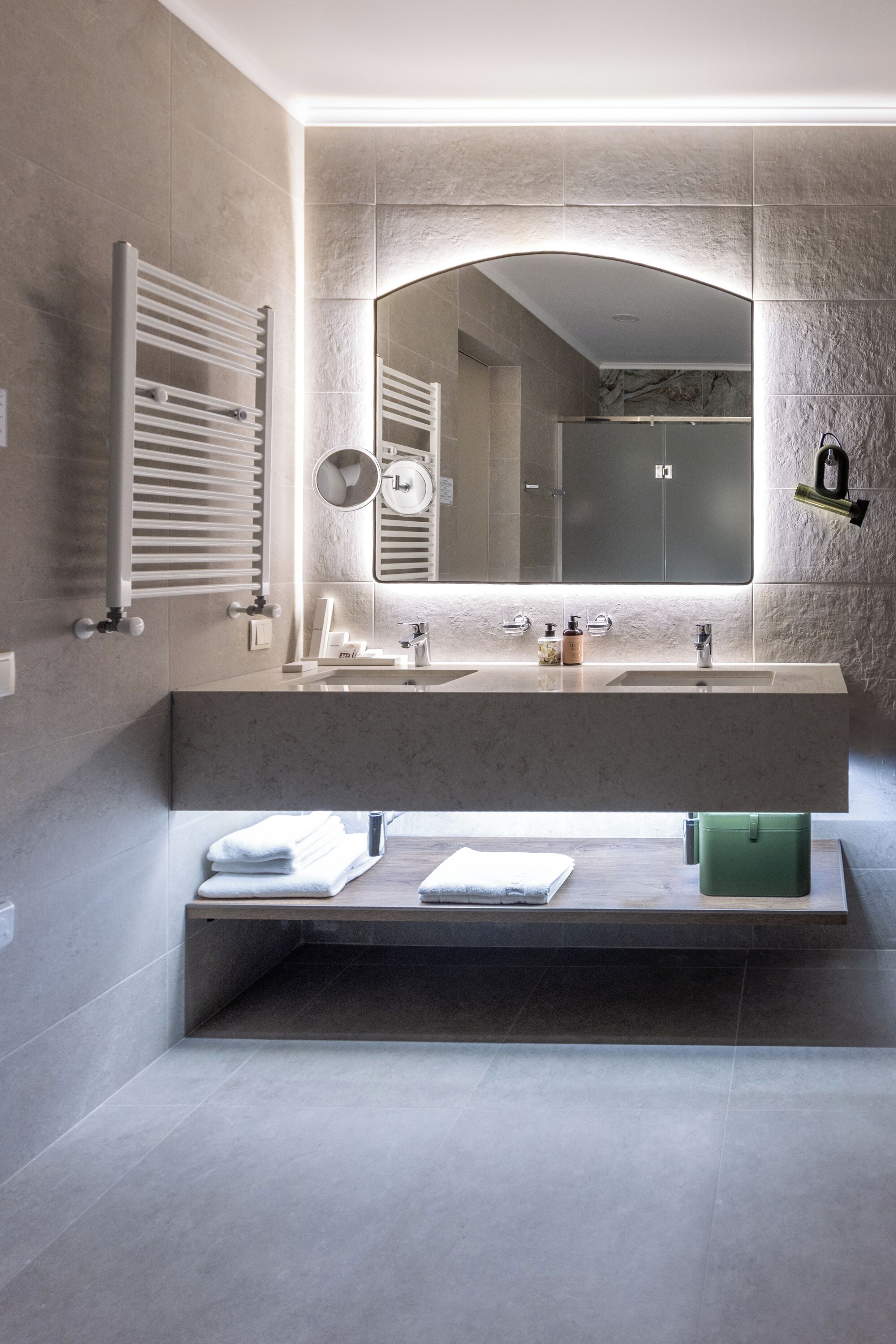 A modern bathroom with a large mirror, dual sinks, and a towel rack.