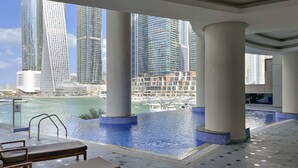 A pool area with lounge chairs, a view of tall buildings, and a water body. - Silkhaus Trident Oceanic - Dubai Marina (Dubai)