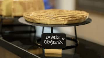 Una presentación de postres con un cartel que dice 'Lovely Crostata' sobre un pedestal negro.