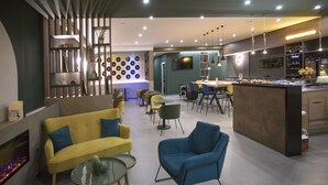 Un interior moderno con un sofá amarillo, un sillón azul y una zona de comedor con sillas y una mesa.