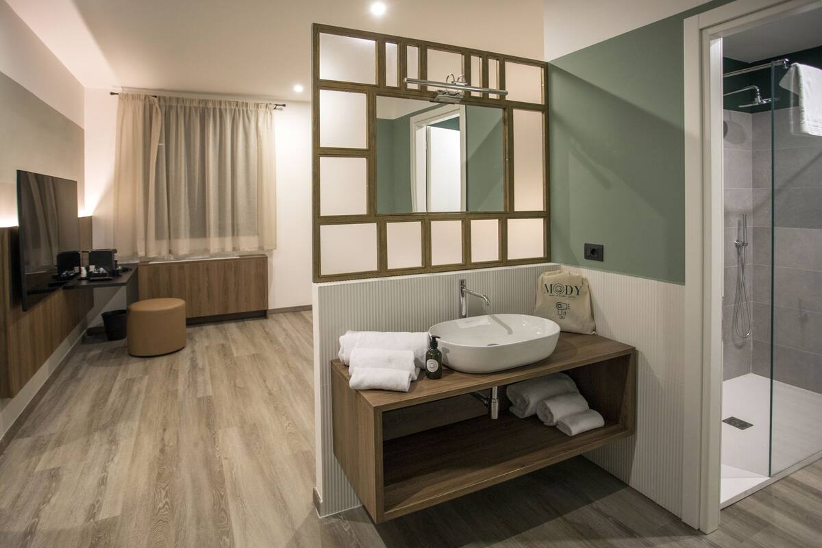 A modern bathroom with a wooden vanity, a large mirror, and a glass shower enclosure.
