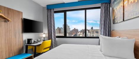 A hotel room with a large bed, a desk with a chair, a television, and a view of the city skyline.