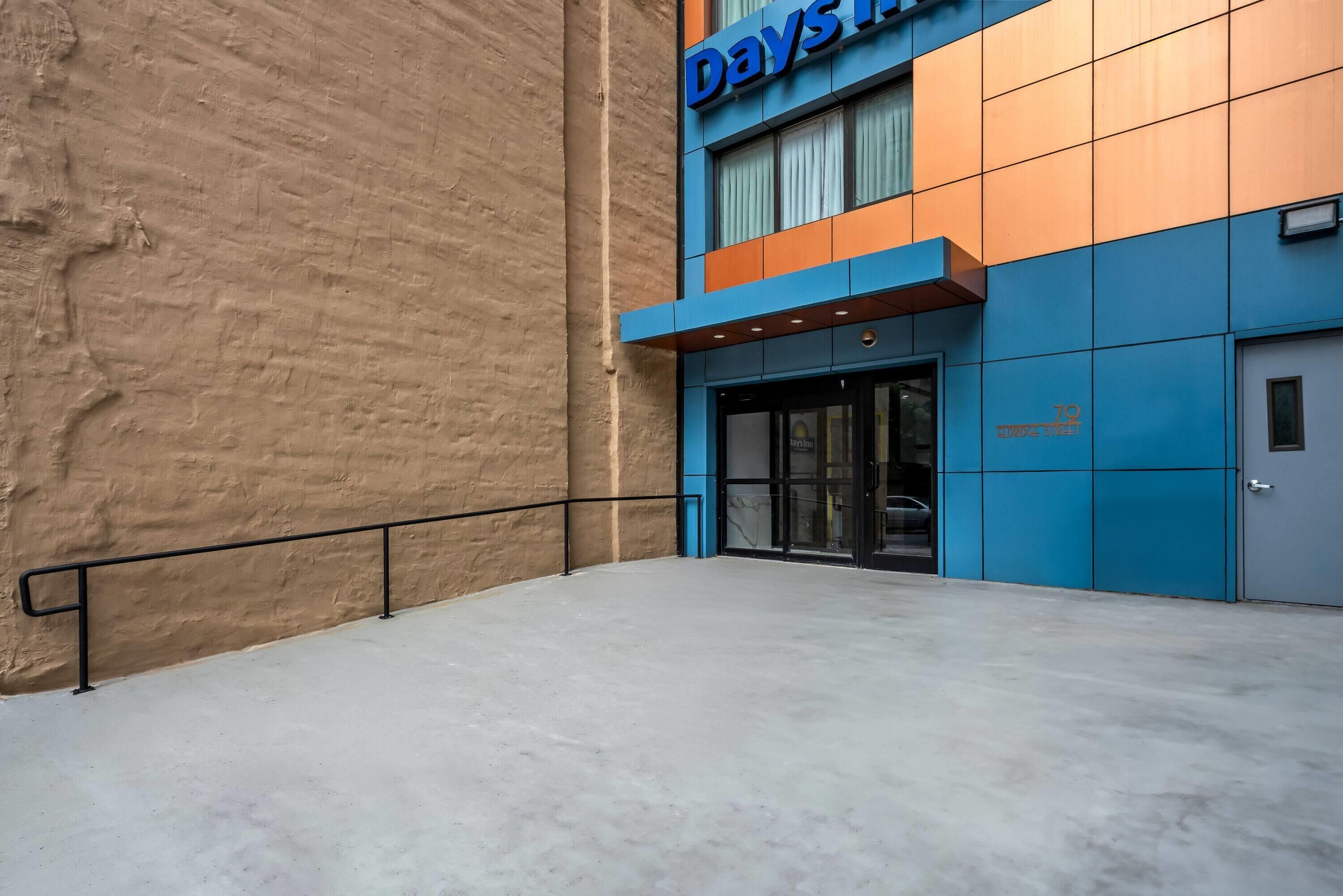 A building with a blue and orange facade, a visible entrance, and a concrete floor.