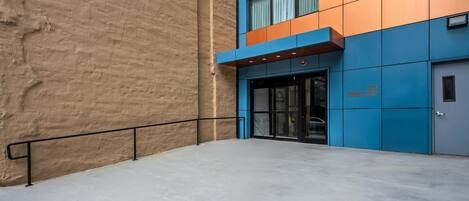 A building with a blue and orange facade, a visible entrance, and a concrete floor.