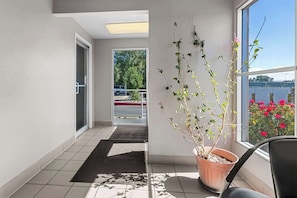 A hotel corridor with a potted plant, a view of the outside, and a door leading to a parking area. - Econo Lodge Idaho Falls, ID (Idaho Falls)