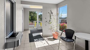 Een moderne kamer met een schuifdeur naar een balkon, een potplant, een zwarte stoel en een klein tafeltje.