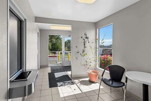 A modern room with a sliding door leading to a balcony, a potted plant, a black chair, and a small table. - Econo Lodge Idaho Falls, ID (Idaho Falls)