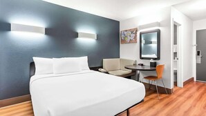 Een hotelkamer met een bed, een bureau, een stoel, een spiegel en een wandlamp.